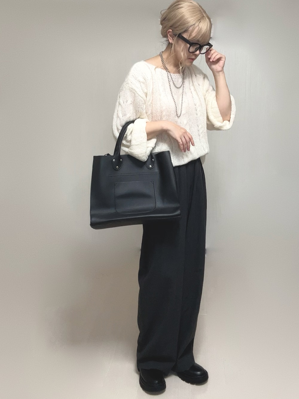 ホワイト系のニット/セーター、ブラック系のブーツ、ブラック系のトートバッグを着用したレディースの夏コーディネートの4枚目の写真