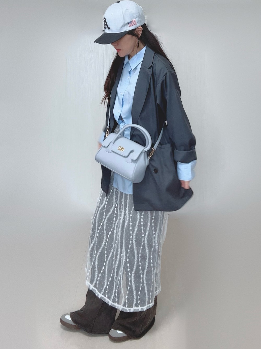 グレー系のテーラードジャケット、ブラック系のスウェットパンツ、ホワイト系のスカートを着用したレディースの春コーディネートの3枚目の写真