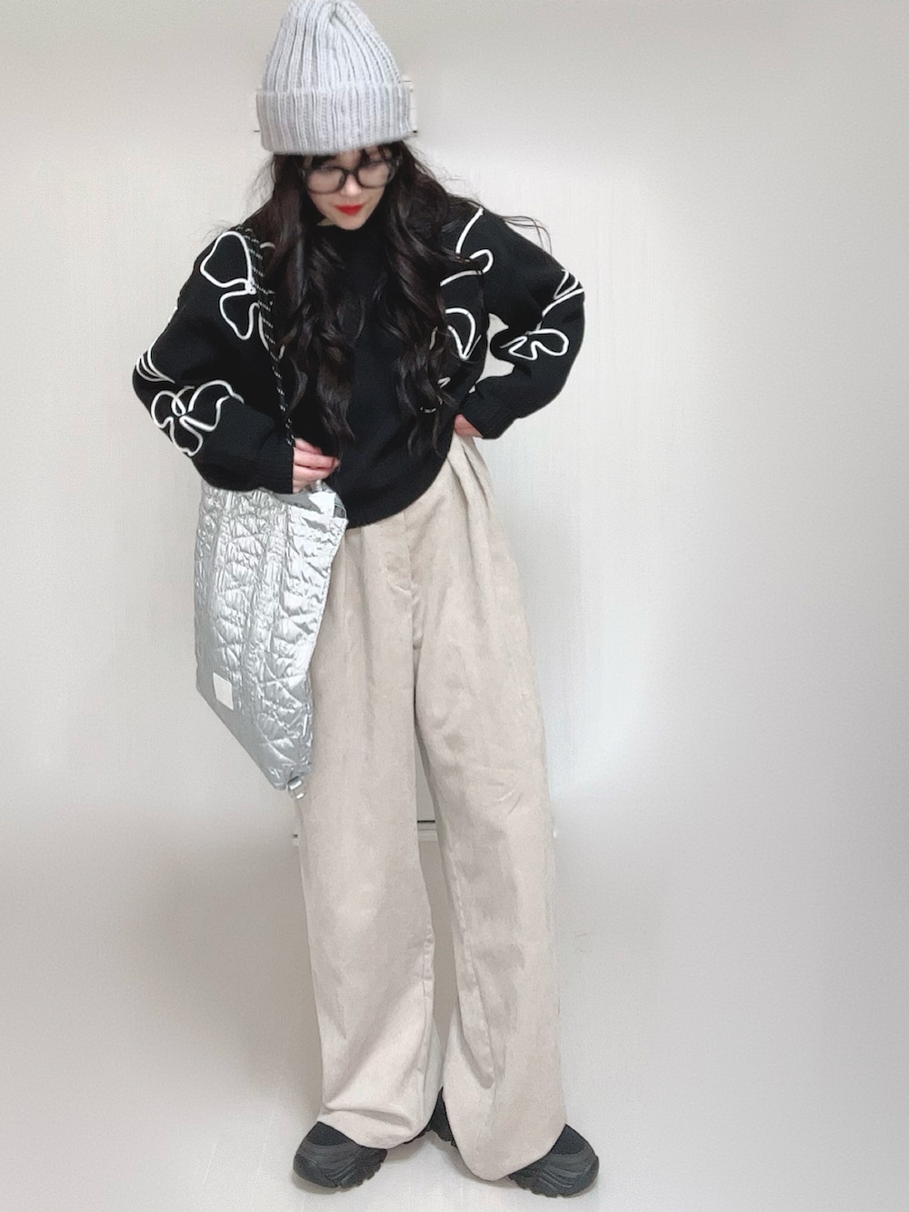 ブラック系のニット/セーター、シルバー系のトートバッグ、ベージュ系のスラックスを着用したレディースの冬コーディネートの2枚目の写真