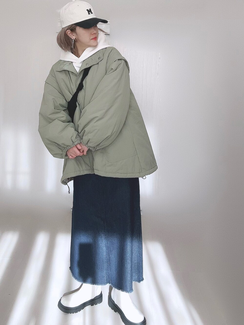 グリーン系のダウンジャケット/コート、ホワイト系のパーカー、ブルー系のセットアップを着用したレディースの冬コーディネートの2枚目の写真