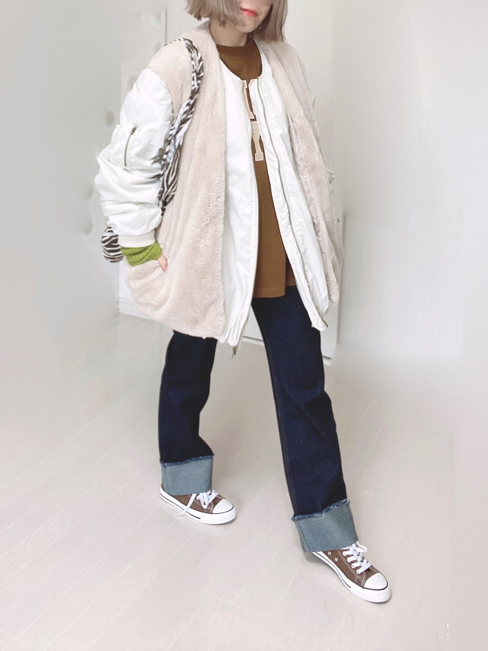 ホワイト系のブルゾン、ブラウン系のTシャツ/カットソー、ブルー系のデニムパンツを着用したレディースの秋コーディネートの2枚目の写真