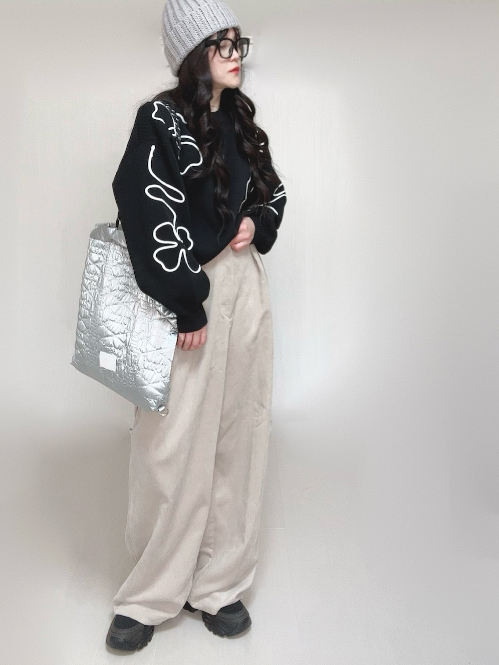 ブラック系のニット/セーター、シルバー系のトートバッグ、ベージュ系のスラックスを着用したレディースの冬コーディネートの3枚目の写真