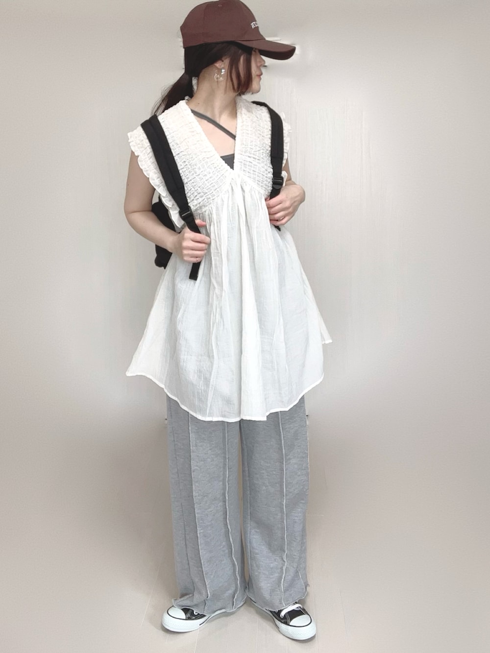 ホワイト系のワンピース、ブラック系のバックパック/リュック、グレー系のスウェットパンツを着用したレディースの春コーディネートの4枚目の写真