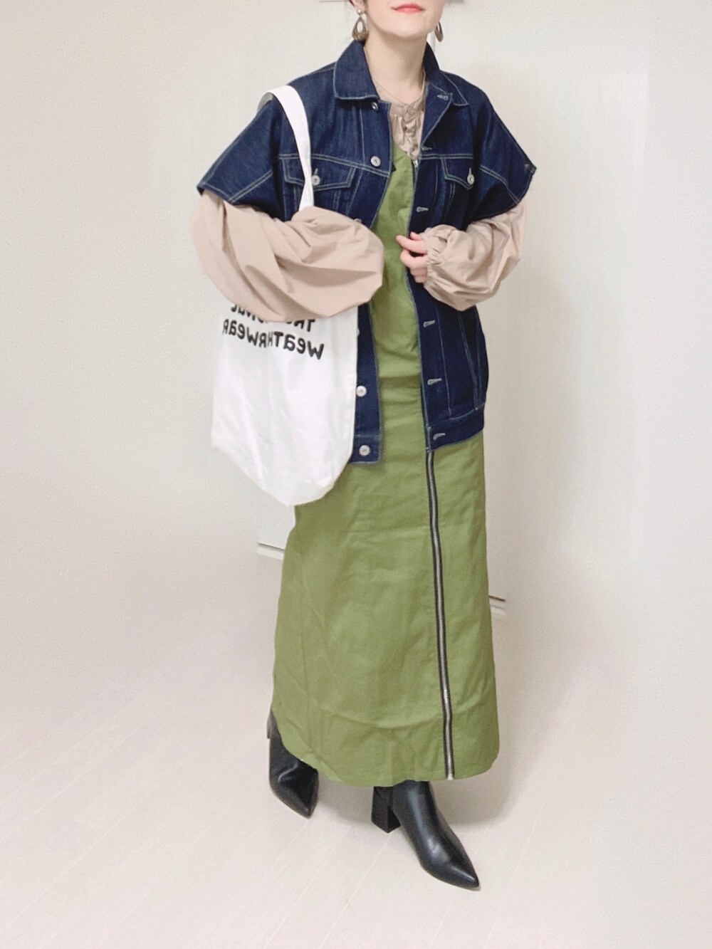 グリーン系のジャンパースカート、ブルー系のベスト、ベージュ系のシャツ/ブラウスを着用したレディースの秋コーディネートの5枚目の写真