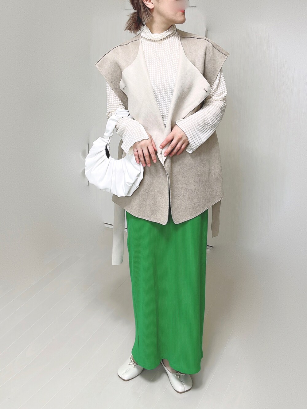 ホワイト系のTシャツ/カットソー、ベージュ系のベスト、グリーン系のスカートを着用したレディースの春コーディネートの5枚目の写真