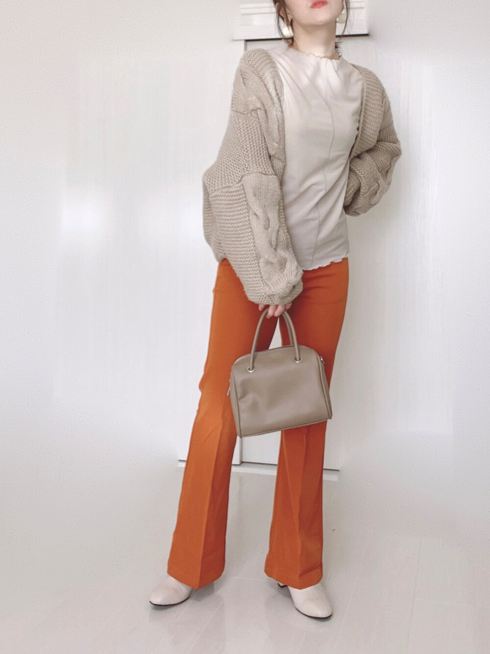 オレンジ系のスラックス、ベージュ系のTシャツ/カットソー、ベージュ系のブーツを着用したレディースの秋コーディネートの2枚目の写真