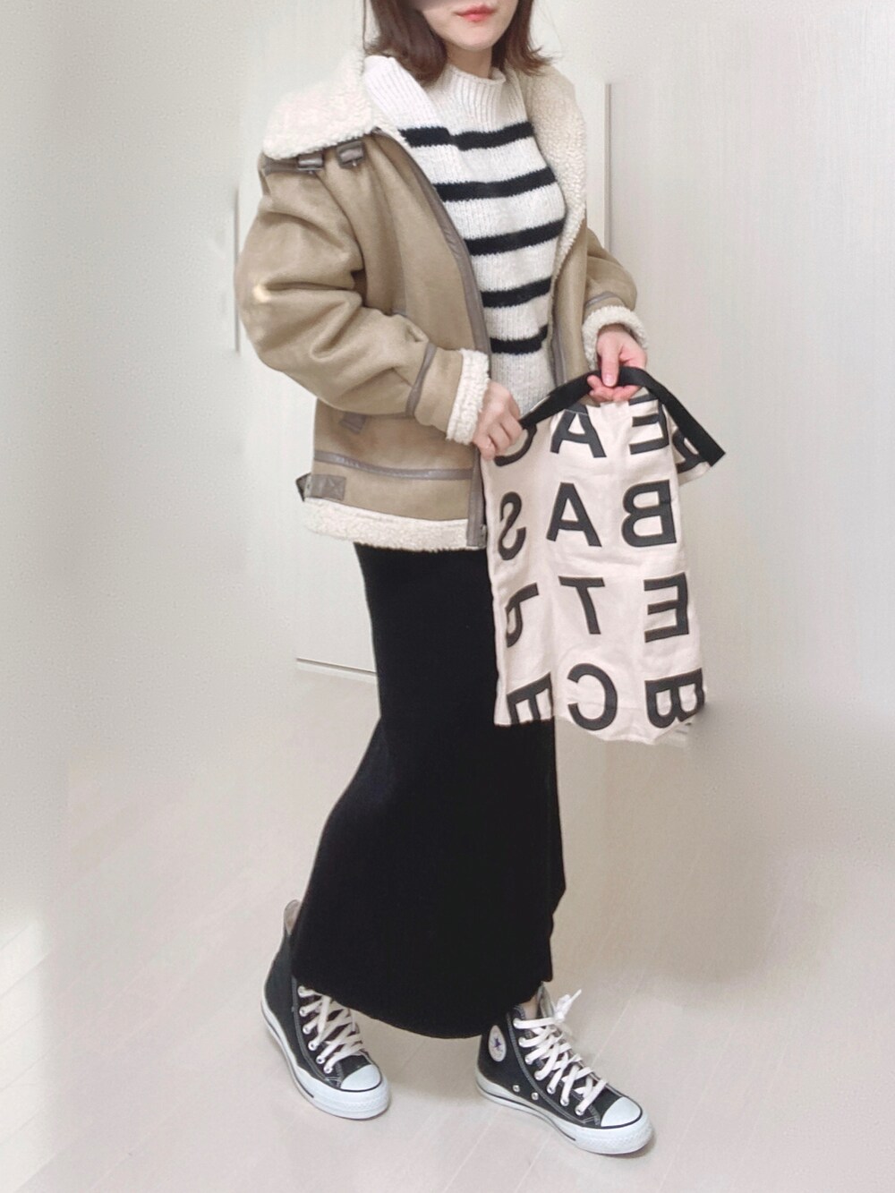 ホワイト系のニット/セーター、ベージュ系のムートンコート、ホワイト系のトートバッグを着用したレディースの冬コーディネートの3枚目の写真