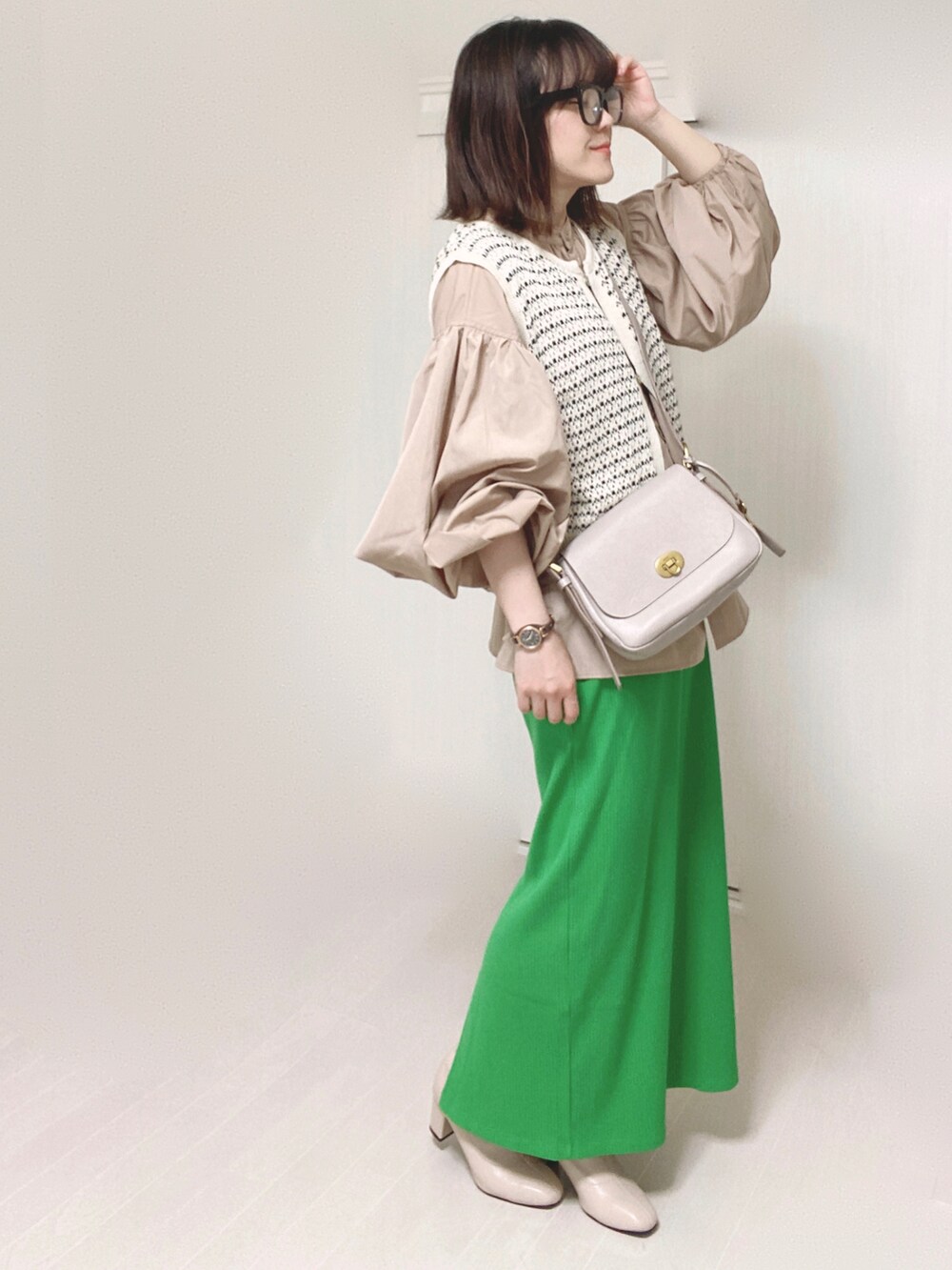 グレー系のメッセンジャーバッグ、ベージュ系のシャツ/ブラウス、グリーン系のスカートを着用したレディースの秋コーディネートの3枚目の写真