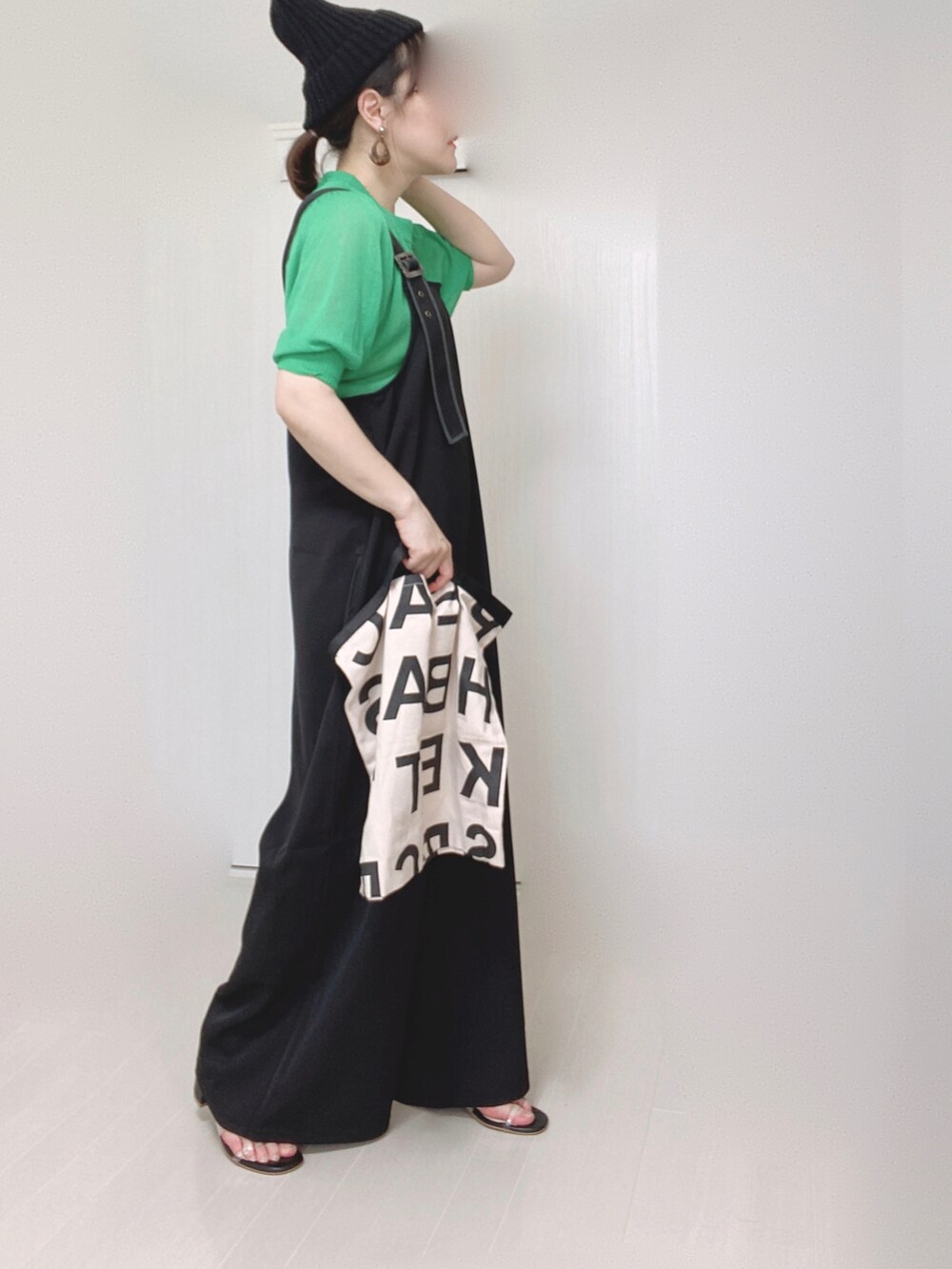 ブラック系のサロペット/オーバーオール、グリーン系のニット/セーター、ホワイト系のトートバッグを着用したレディースの夏コーディネートの4枚目の写真