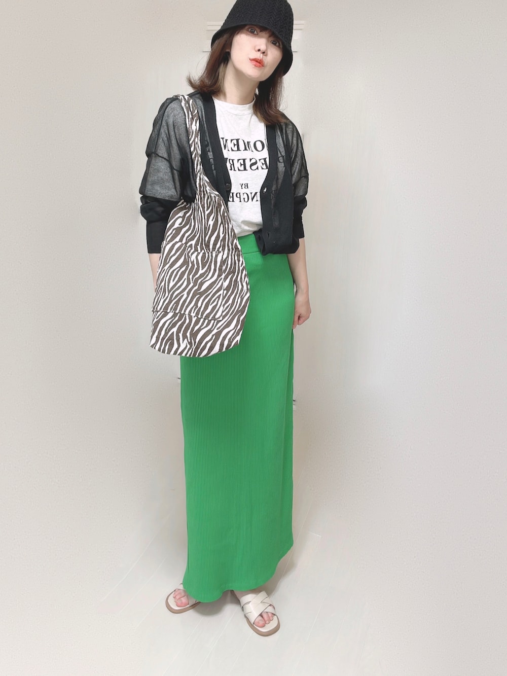 ブラック系のカーディガン/ボレロ、グリーン系のスカート、ホワイト系のサンダルを着用したレディースの夏コーディネートの3枚目の写真