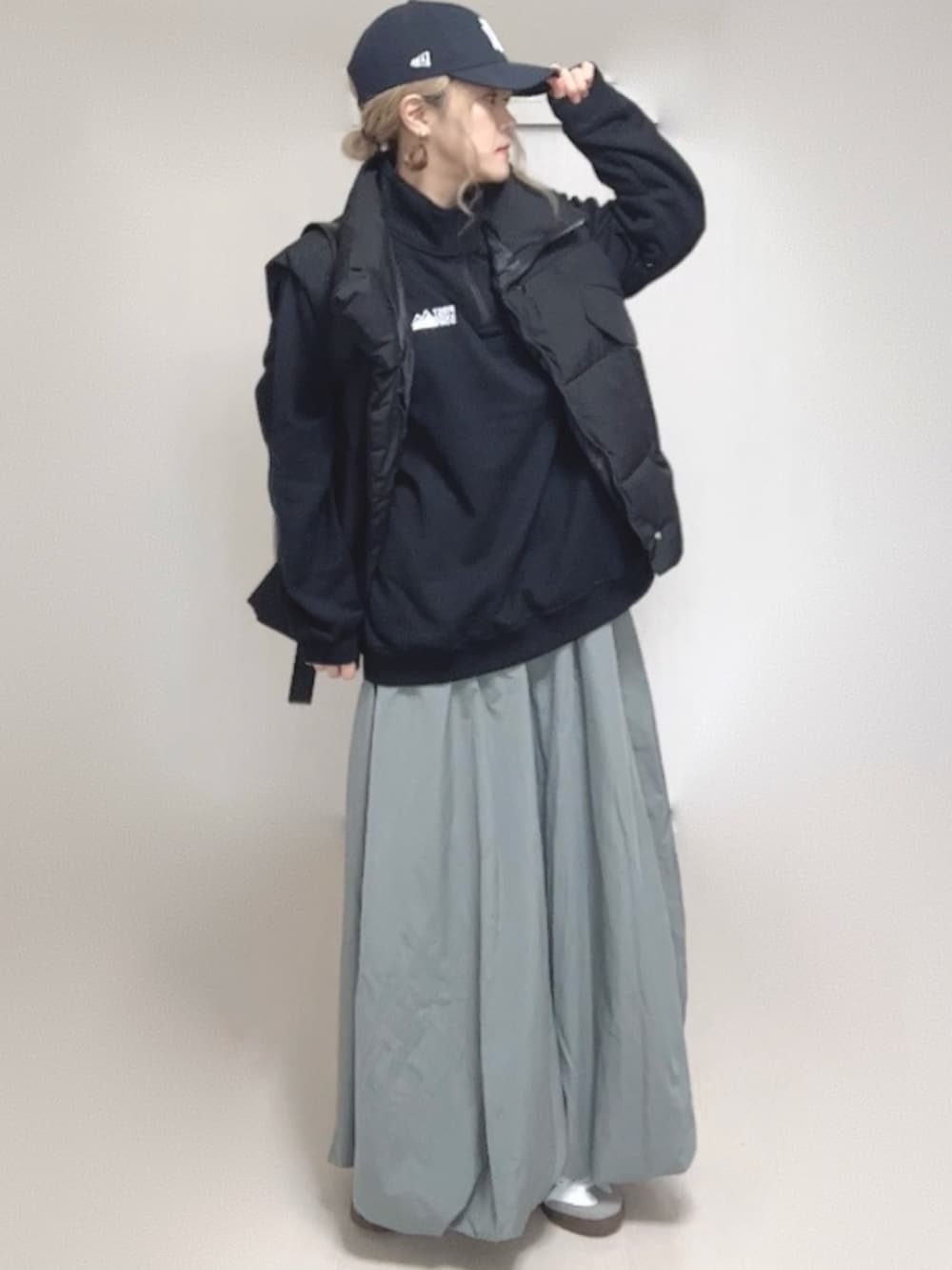 ブラック系のダウンベスト、ブラック系のスウェット、ブルー系のキャップを着用したレディースの秋コーディネートの4枚目の写真