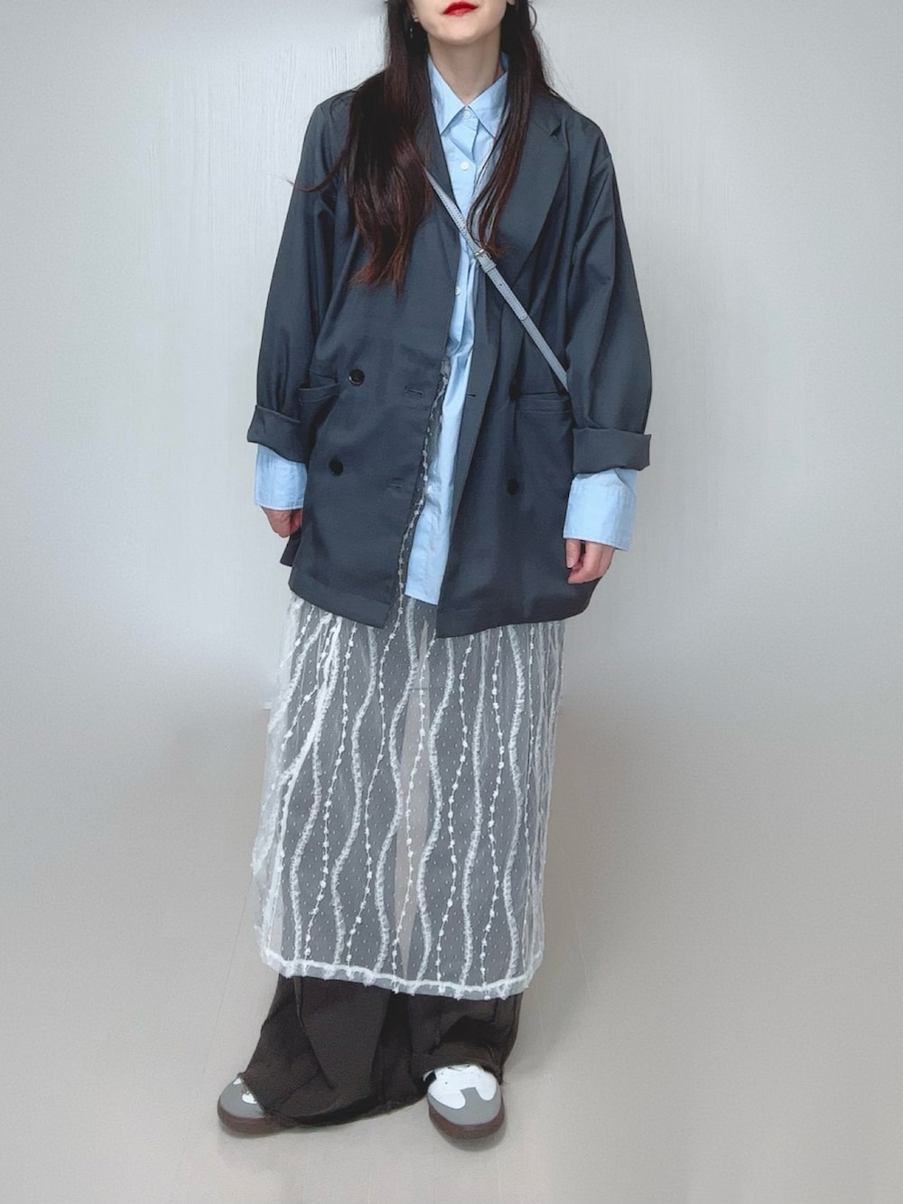 グレー系のテーラードジャケット、ブラック系のスウェットパンツ、ホワイト系のスカートを着用したレディースの春コーディネートの4枚目の写真