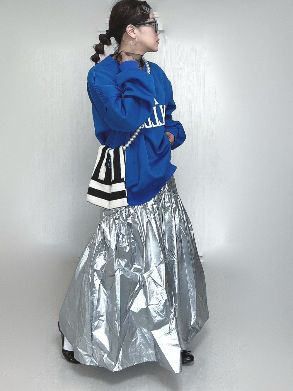 シルバー系のスカート、ブラック系のTシャツ/カットソー、ホワイト系のショルダーバッグを着用したレディースの春コーディネートの3枚目の写真