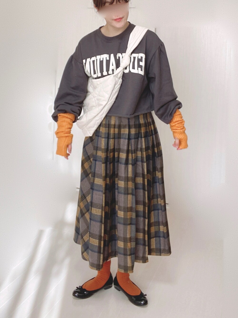 ホワイト系のショルダーバッグ、イエロー系のスカート、ブラック系のバレエシューズを着用したレディースの冬コーディネートの4枚目の写真