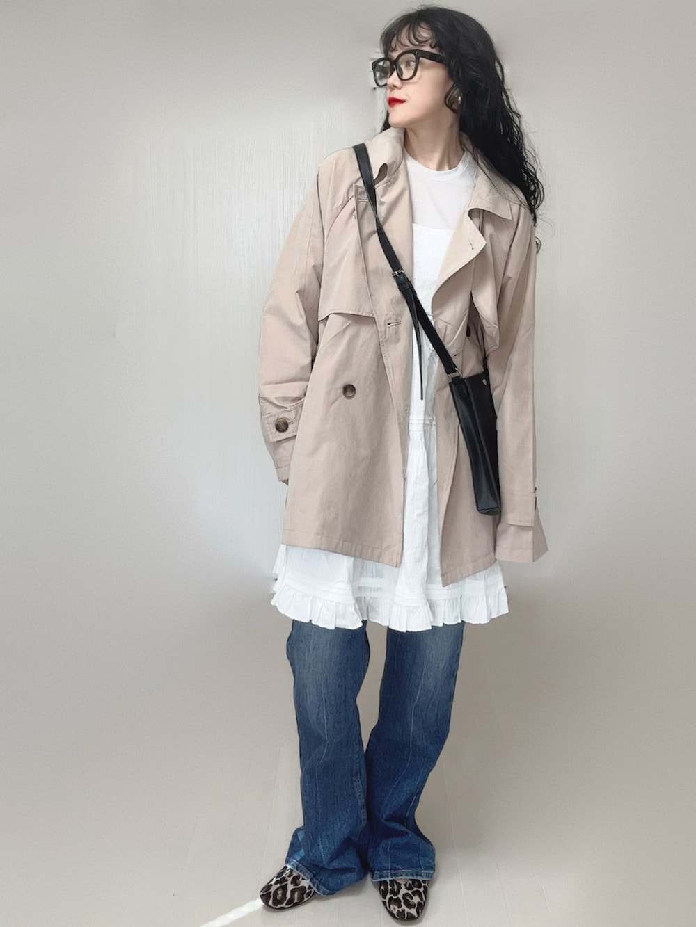 ベージュ系のトレンチコート、ホワイト系のワンピース、ブラック系のショルダーバッグを着用したレディースの春コーディネートの5枚目の写真