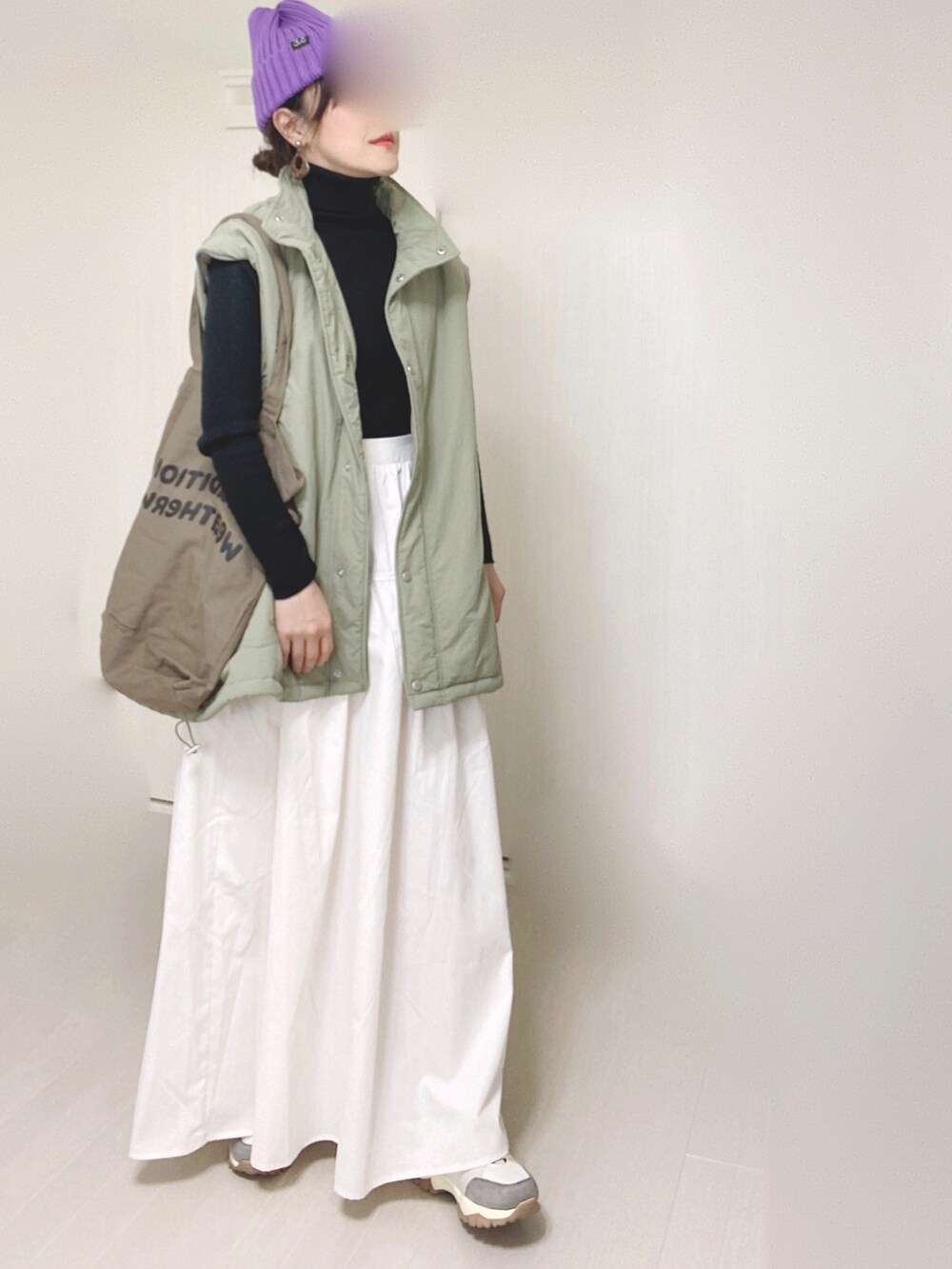グリーン系のダウンジャケット/コート、ホワイト系のスカート、ベージュ系のスニーカーを着用したレディースの秋コーディネートの4枚目の写真