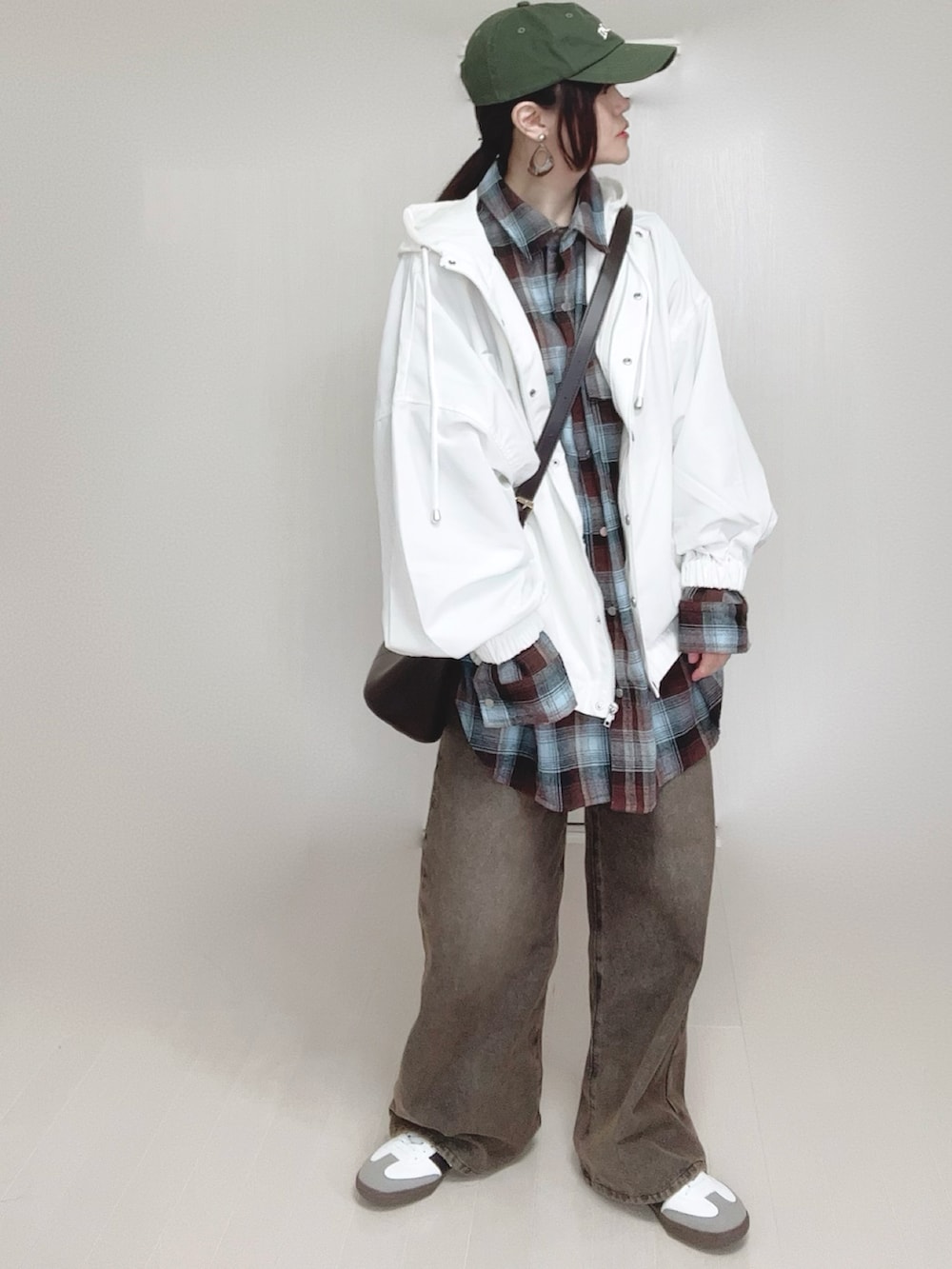 ホワイト系のマウンテンパーカー、ブラウン系のシャツ/ブラウス、ブラック系のデニムパンツを着用したレディースの春コーディネートの5枚目の写真