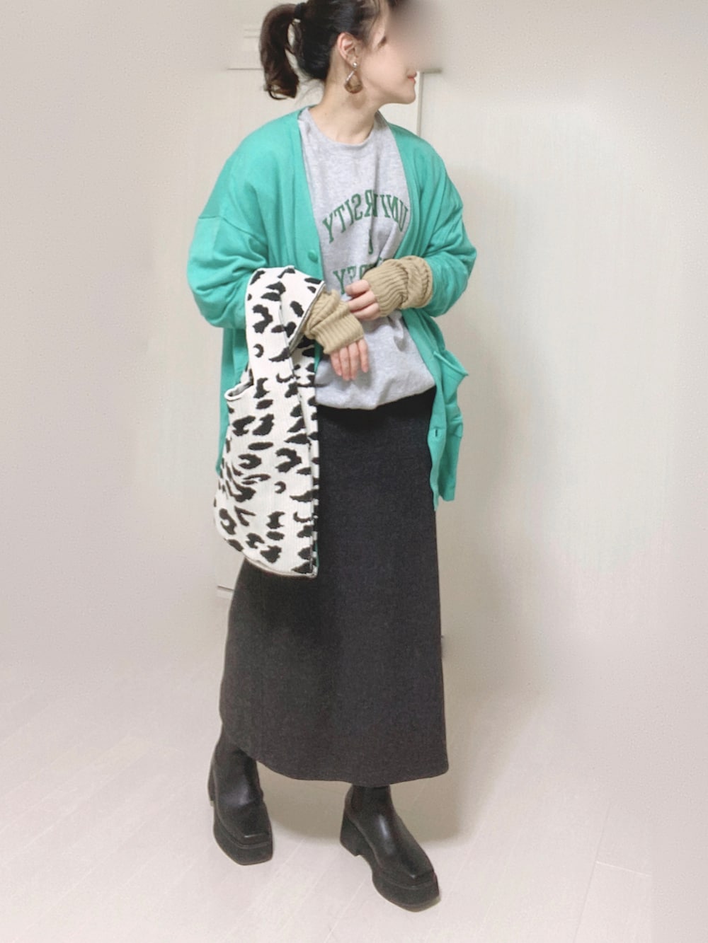 グレー系のスウェット、グリーン系のカーディガン/ボレロ、ブラック系のブーツを着用したレディースの冬コーディネートの4枚目の写真