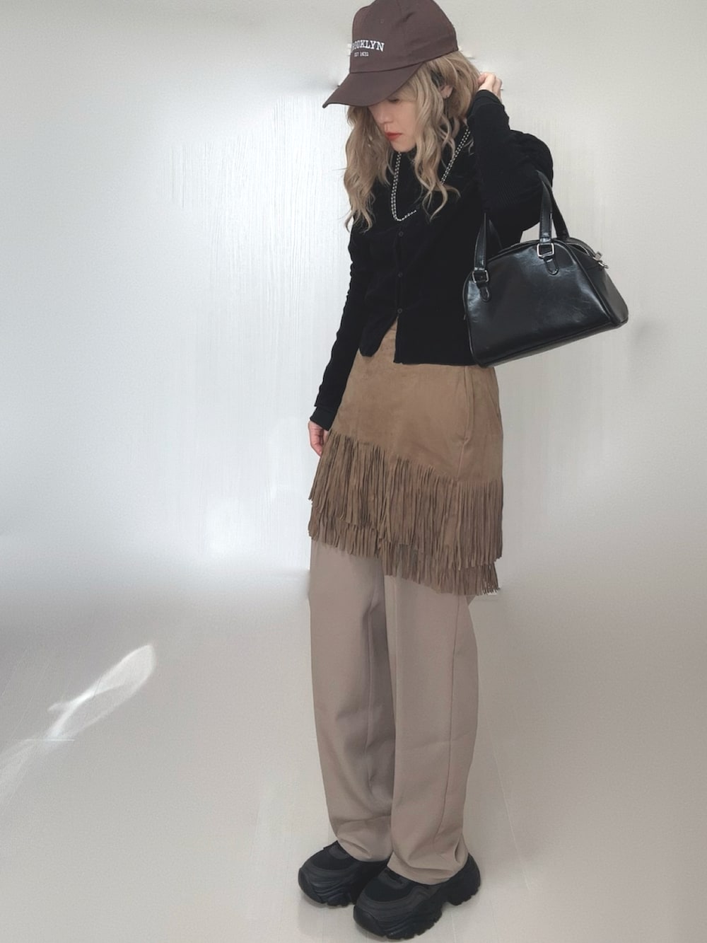 ブラック系のカーディガン/ボレロ、ブラック系のTシャツ/カットソー、ベージュ系のスカートを着用したレディースの冬コーディネートの5枚目の写真