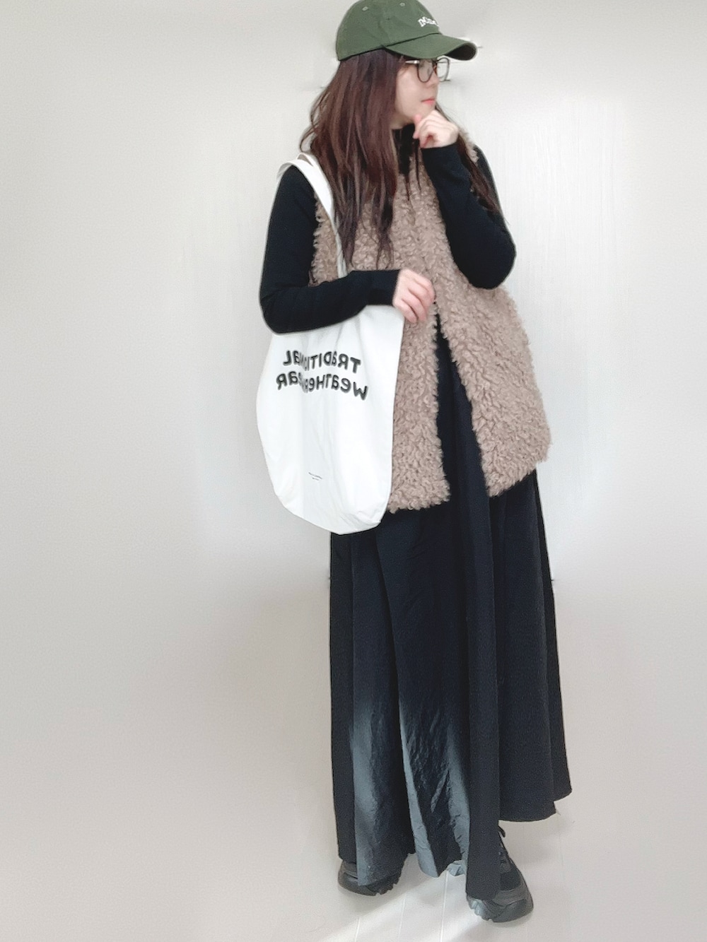 グレー系のワンピース、ベージュ系のベスト、ホワイト系のトートバッグを着用したレディースの冬コーディネートの2枚目の写真