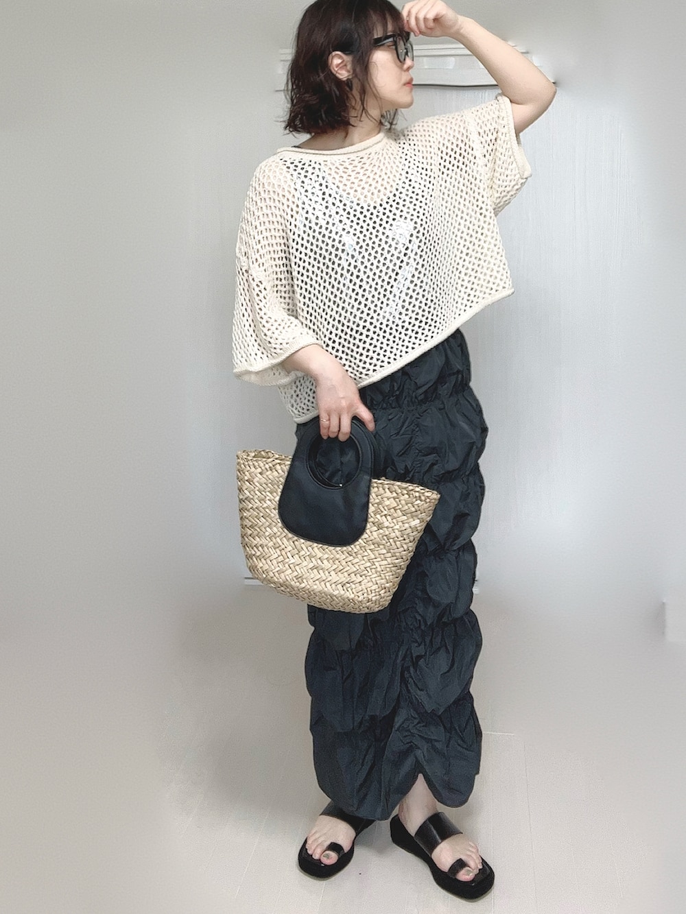 グレー系のスカート、シルバー系のタンクトップ、ベージュ系のニット/セーターを着用したレディースの春コーディネートの2枚目の写真