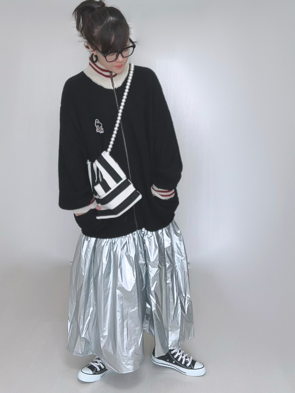 ブラック系のニット/セーター、ホワイト系のショルダーバッグ、シルバー系のスカートを着用したレディースの冬コーディネートの2枚目の写真