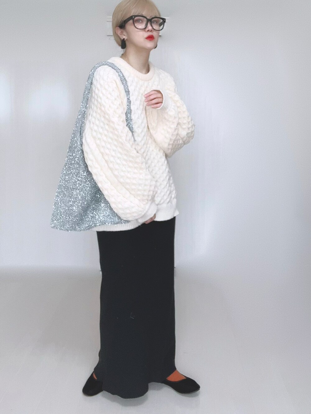 ホワイト系のニット/セーター、ブラック系のスカート、ブラック系のパンプスを着用したレディースの冬コーディネートの4枚目の写真