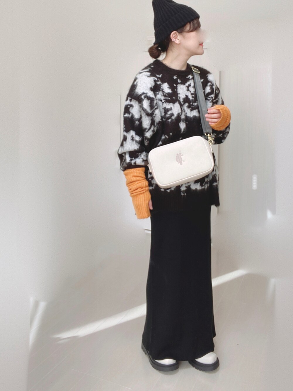 ホワイト系のショルダーバッグ、ブラック系のニット/セーター、ブラック系のスカートを着用したレディースの冬コーディネートの3枚目の写真