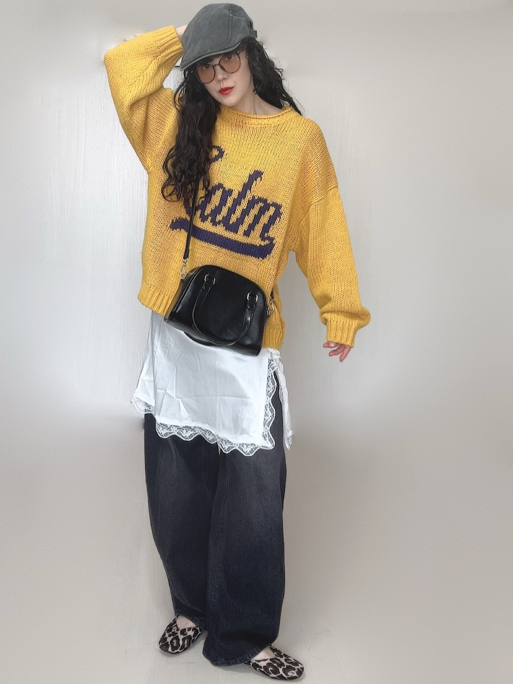 イエロー系のニット/セーター、ブラック系のデニムパンツ、ホワイト系のワンピースを着用したレディースの春コーディネートの3枚目の写真