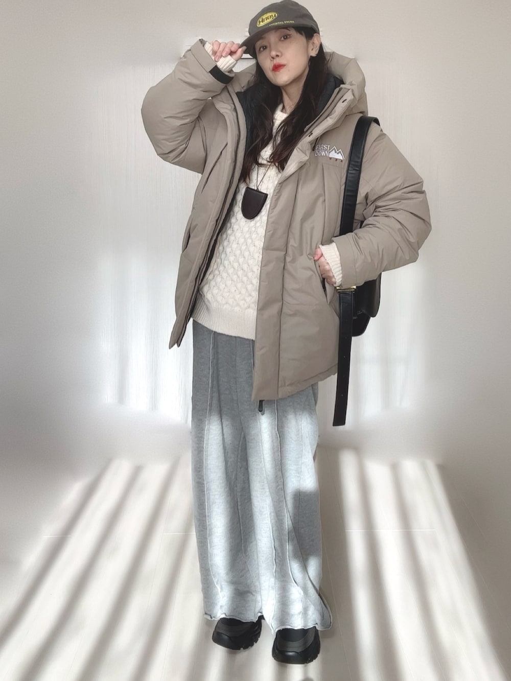 ベージュ系のダウンジャケット/コート、グレー系のスウェットパンツ、ホワイト系のニット/セーターを着用したレディースの冬コーディネートの5枚目の写真