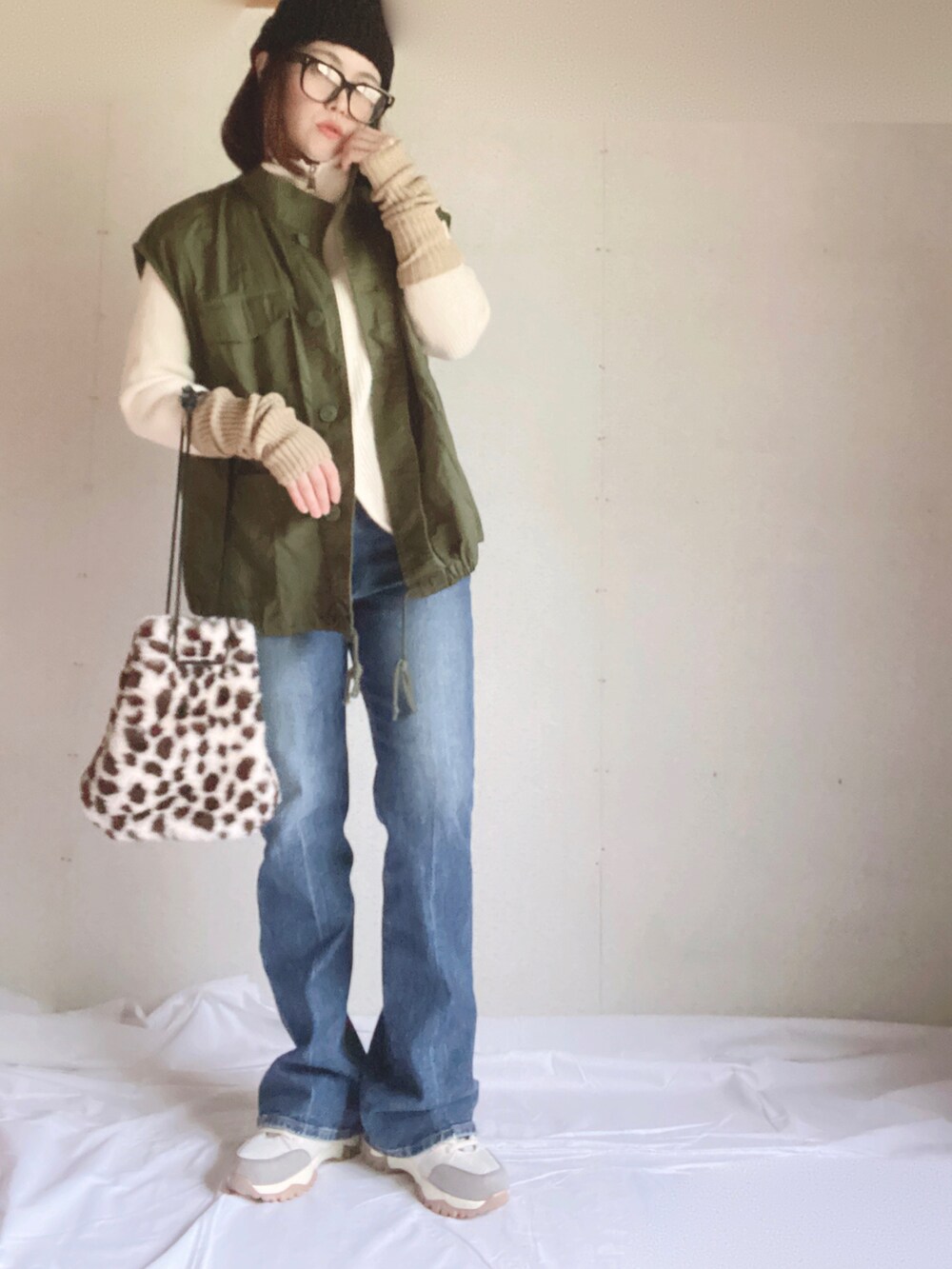 ブルー系のデニムパンツ、ベージュ系のスニーカー、ホワイト系のニット/セーターを着用したレディースの秋コーディネートの3枚目の写真