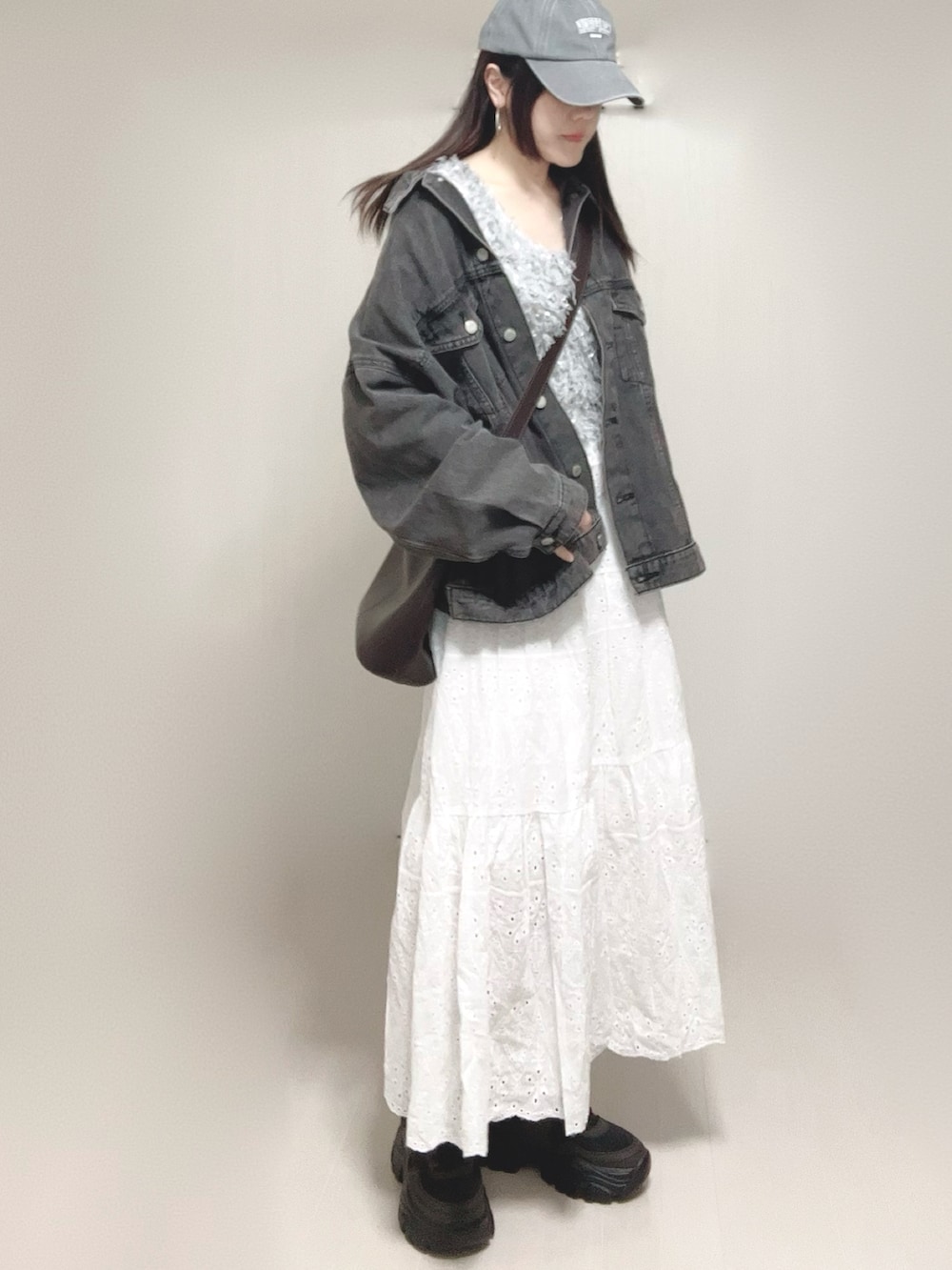 グレー系のベスト、ブラック系のデニムジャケット、ホワイト系のスカートを着用したレディースの春コーディネートの2枚目の写真