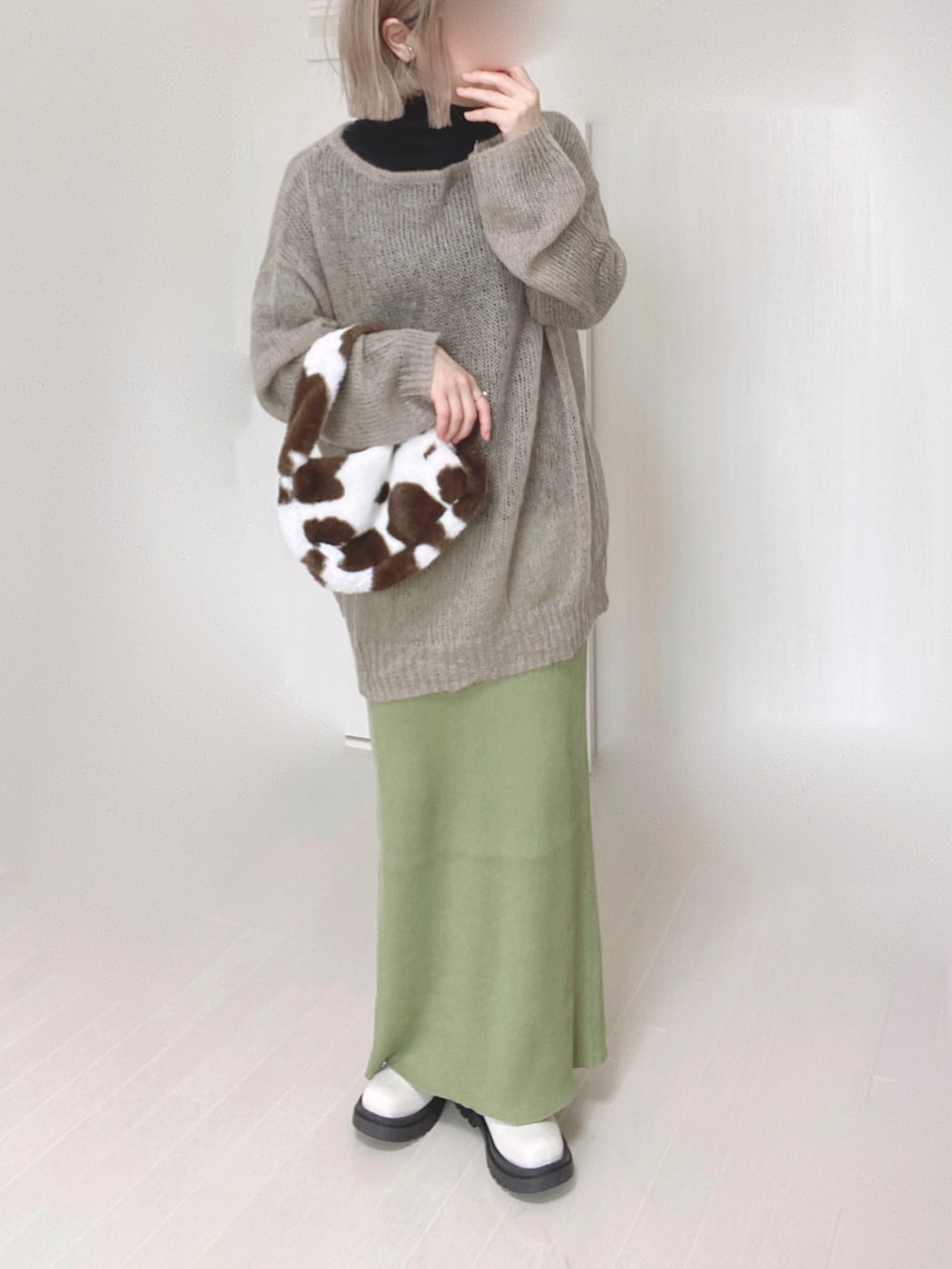 グリーン系のスカート、ベージュ系のニット/セーター、ホワイト系のブーツを着用したレディースの秋コーディネートの4枚目の写真