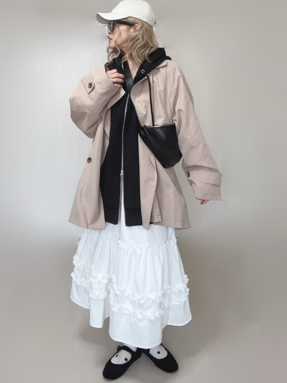 ブラック系のパーカー、ホワイト系のスカート、ベージュ系のトレンチコートを着用したレディースの春コーディネートの3枚目の写真