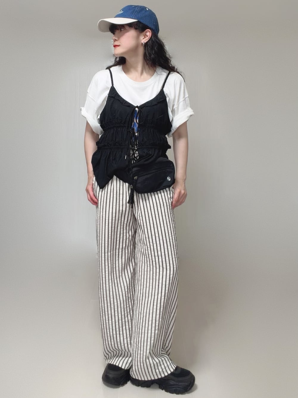 ブラック系のキャミソール、ブラック系のボディバッグ/ウエストポーチ、ホワイト系のTシャツ/カットソーを着用したレディースの夏コーディネートの4枚目の写真