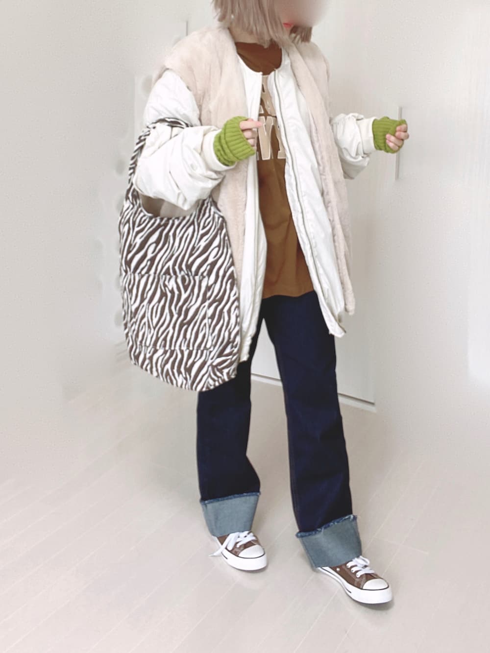 ホワイト系のブルゾン、ブラウン系のTシャツ/カットソー、ブルー系のデニムパンツを着用したレディースの秋コーディネートの3枚目の写真