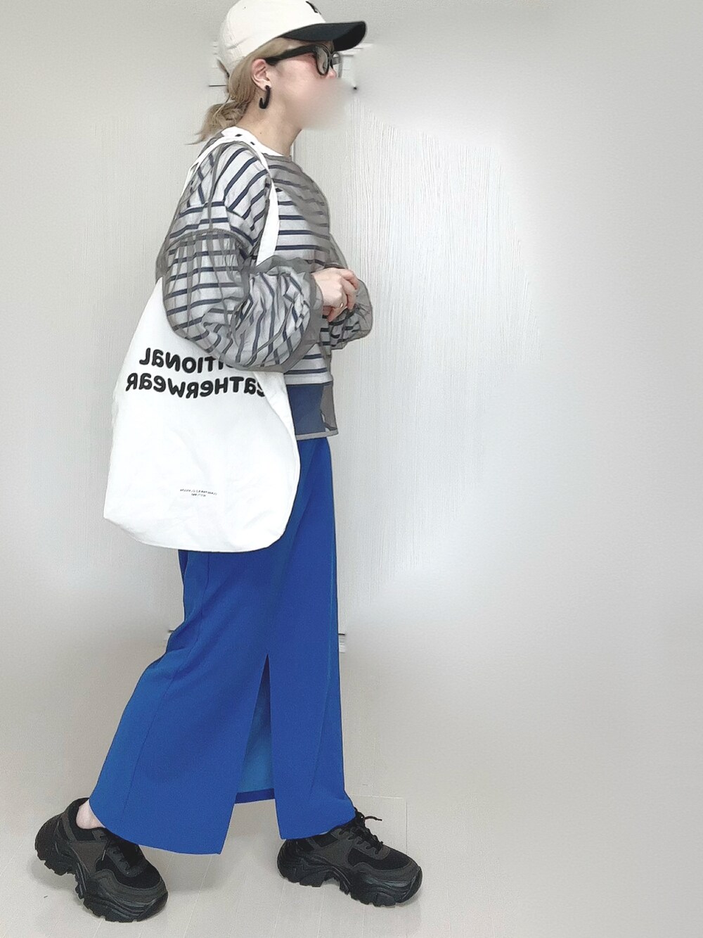 ブルー系のスカート、ホワイト系のトートバッグ、ブラック系のスニーカーを着用したレディースの春コーディネートの5枚目の写真