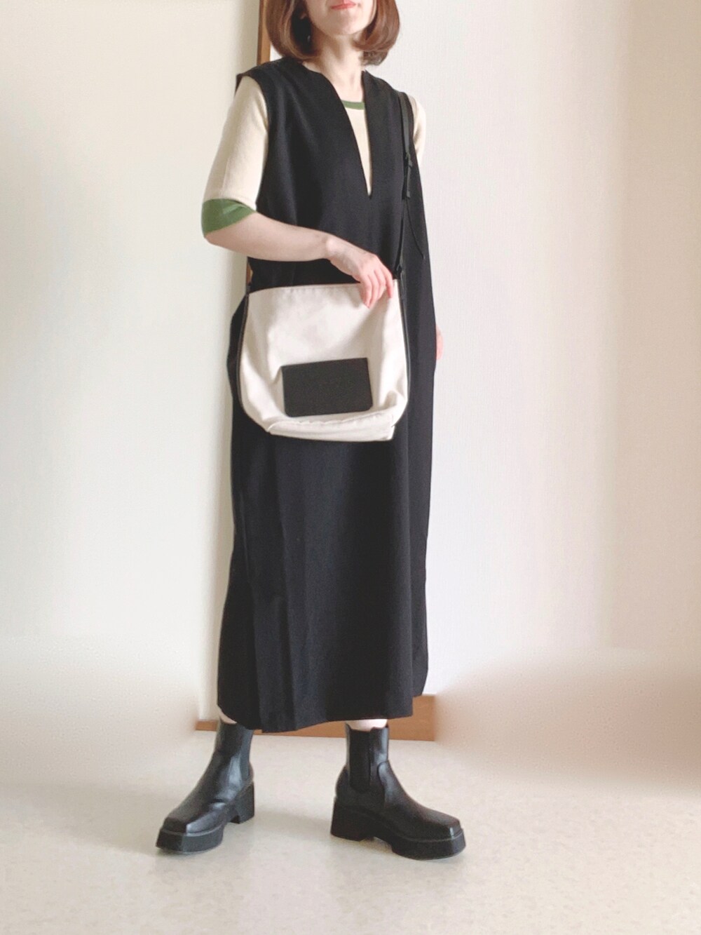 ホワイト系のショルダーバッグ、ブラック系のワンピース、ブラック系のブーツを着用したレディースの秋コーディネートの4枚目の写真