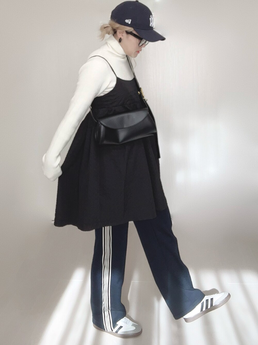 ブルー系のスウェットパンツ、ホワイト系のニット/セーター、ブラック系のワンピースを着用したレディースの春コーディネートの2枚目の写真