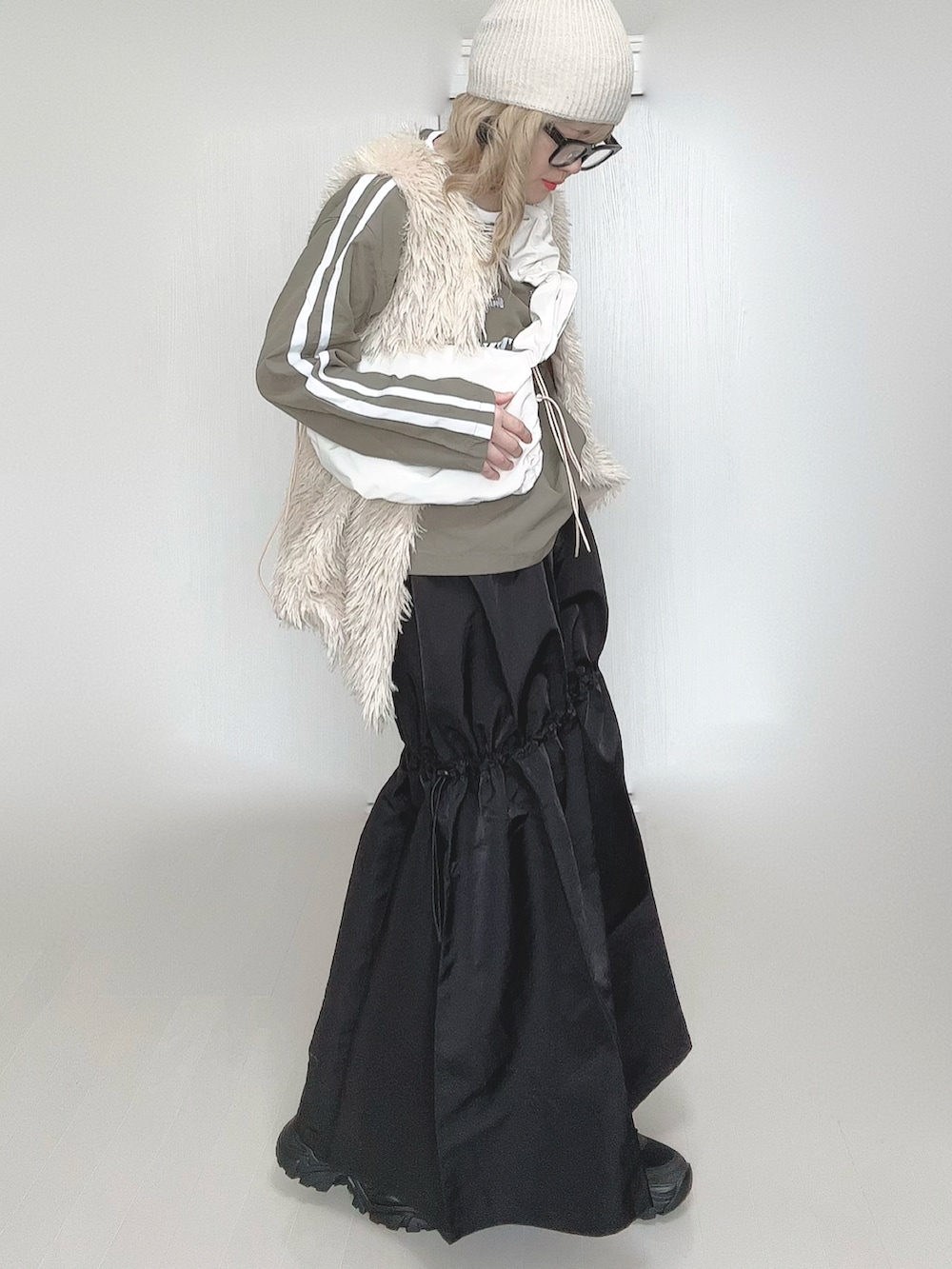 ホワイト系のショルダーバッグ、ホワイト系のベスト、ブラック系のスカートを着用したレディースの春コーディネートの3枚目の写真