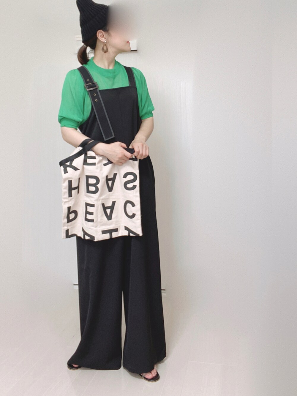 ブラック系のサロペット/オーバーオール、グリーン系のニット/セーター、ホワイト系のトートバッグを着用したレディースの夏コーディネートの2枚目の写真