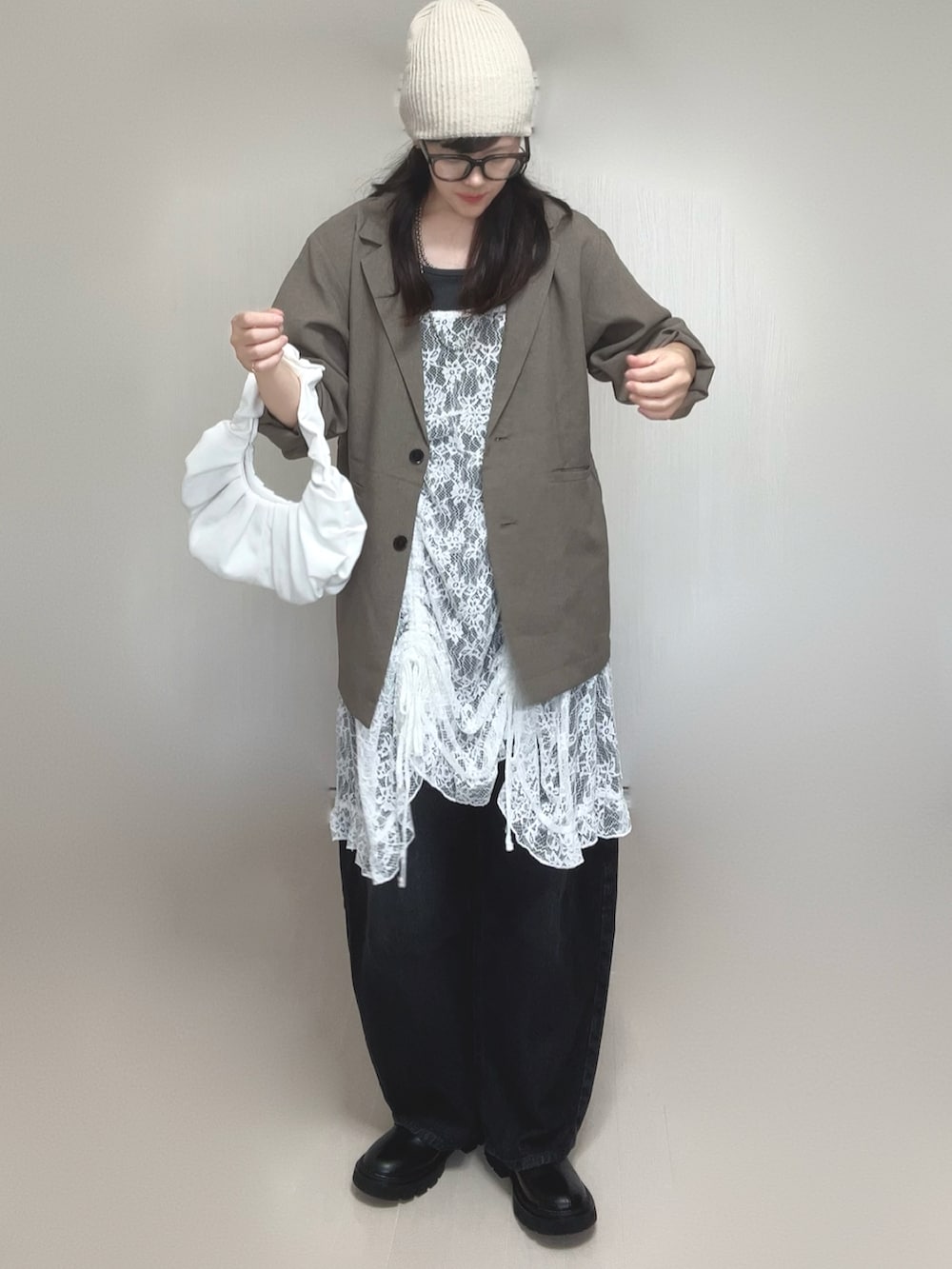 ベージュ系のテーラードジャケット、ホワイト系のチュニック、ブラック系のブーツを着用したレディースの夏コーディネートの2枚目の写真