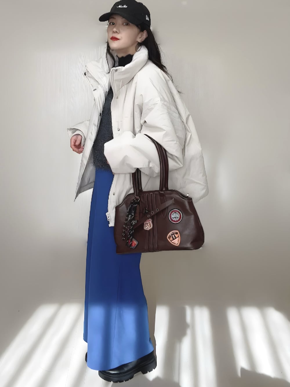 ホワイト系のブルゾン、ブラック系のブーツ、グレー系のベストを着用したレディースの秋コーディネートの3枚目の写真