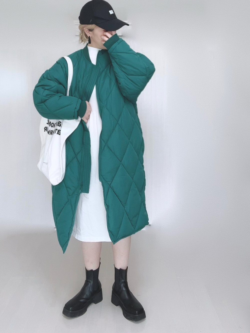 グリーン系のダウンジャケット/コート、ホワイト系のワンピース、ホワイト系のトートバッグを着用したレディースの冬コーディネートの3枚目の写真