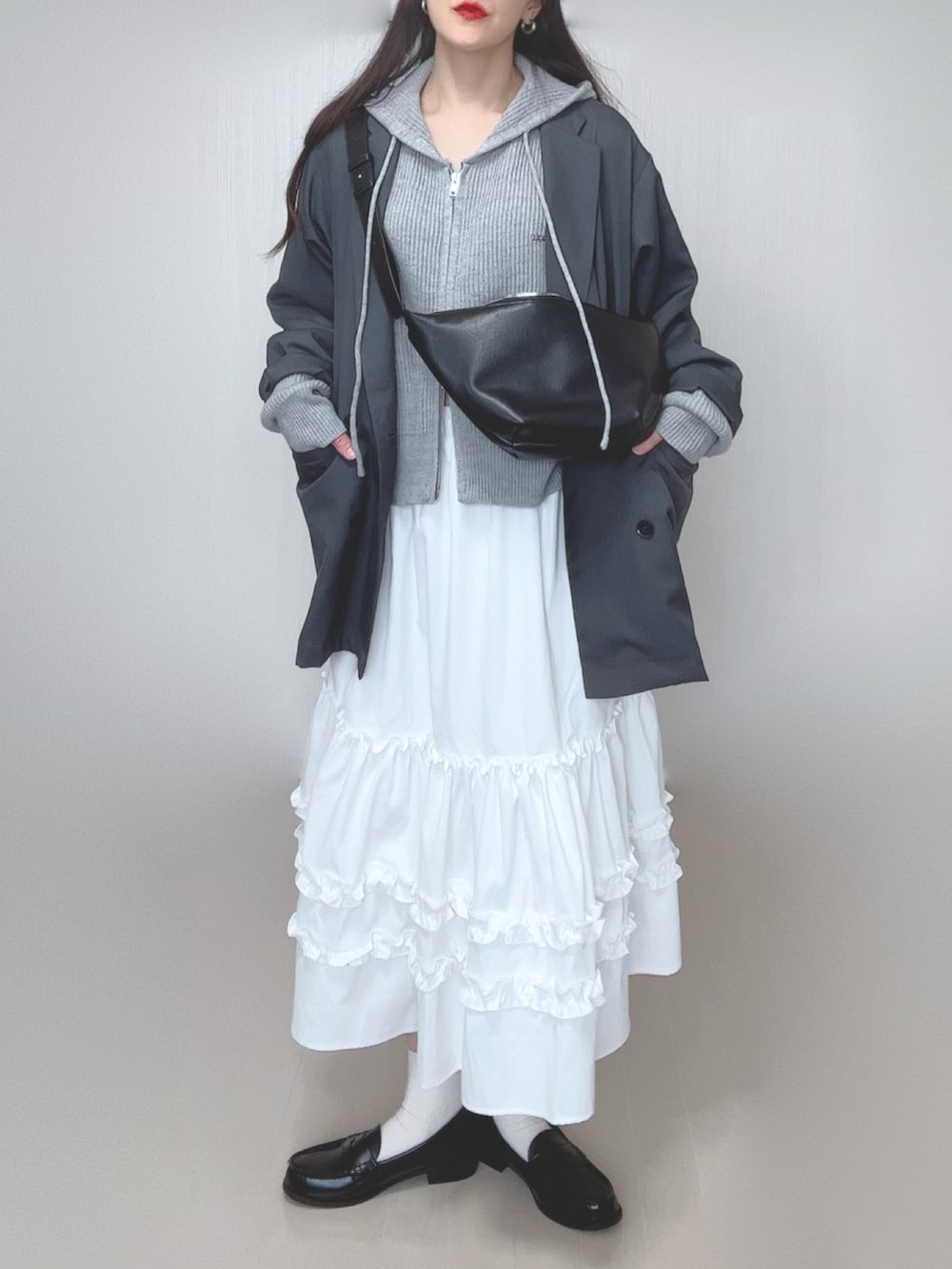 グレー系のパーカー、グレー系のテーラードジャケット、ホワイト系のスカートを着用したレディースの春コーディネートの3枚目の写真