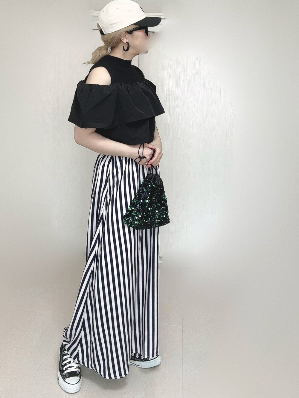 ブルー系のスカート、ブラック系のスニーカー、ブラック系のキャップを着用したレディースの春コーディネートの5枚目の写真