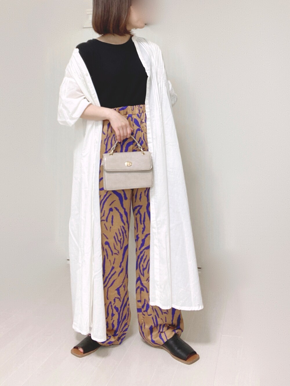 ホワイト系のシャツワンピース、オレンジ系のその他パンツ、ベージュ系のショルダーバッグを着用したレディースの夏コーディネートの3枚目の写真
