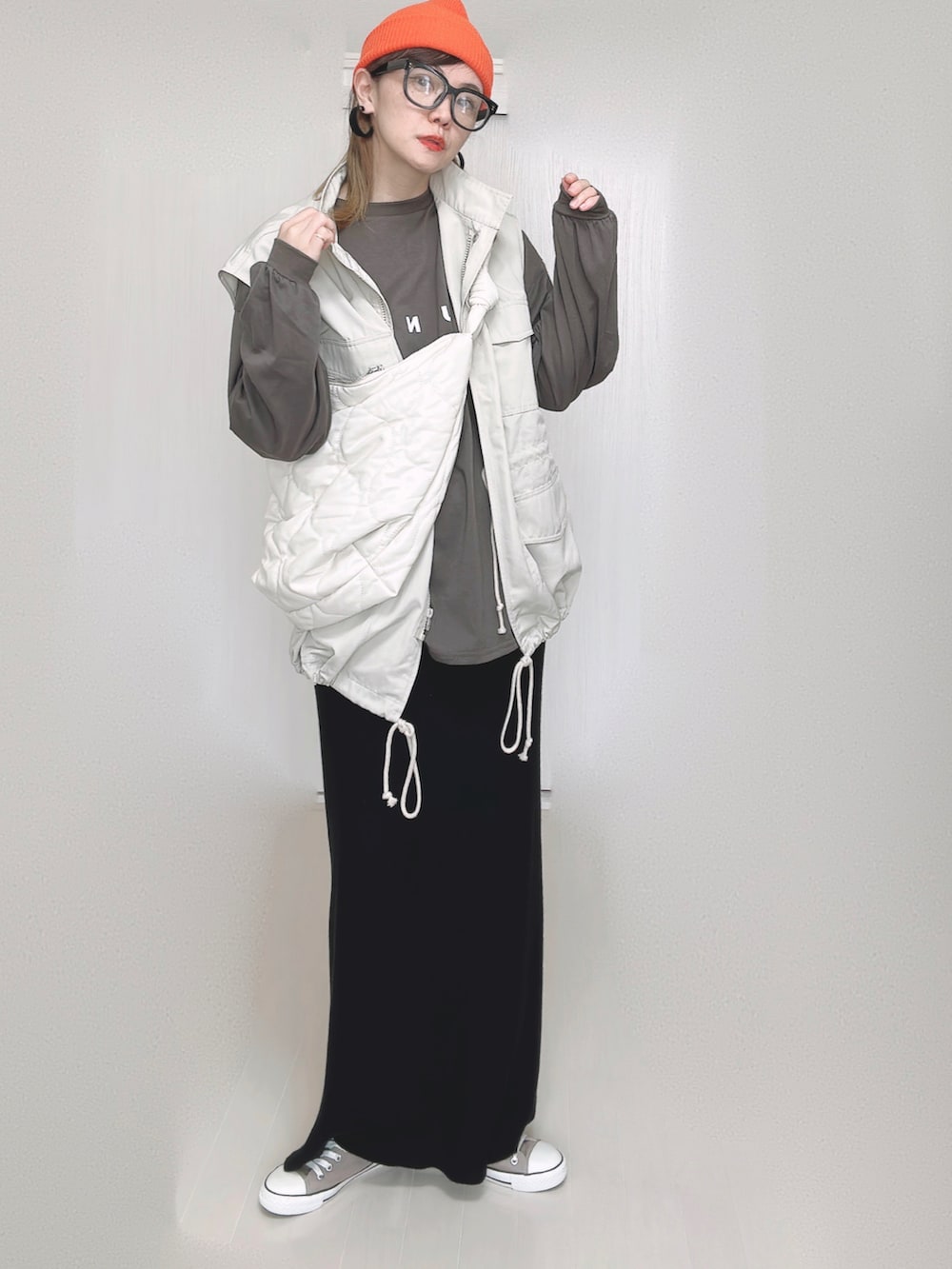 ホワイト系のショルダーバッグ、ホワイト系のベスト、ブラック系のスカートを着用したレディースの秋コーディネートの4枚目の写真