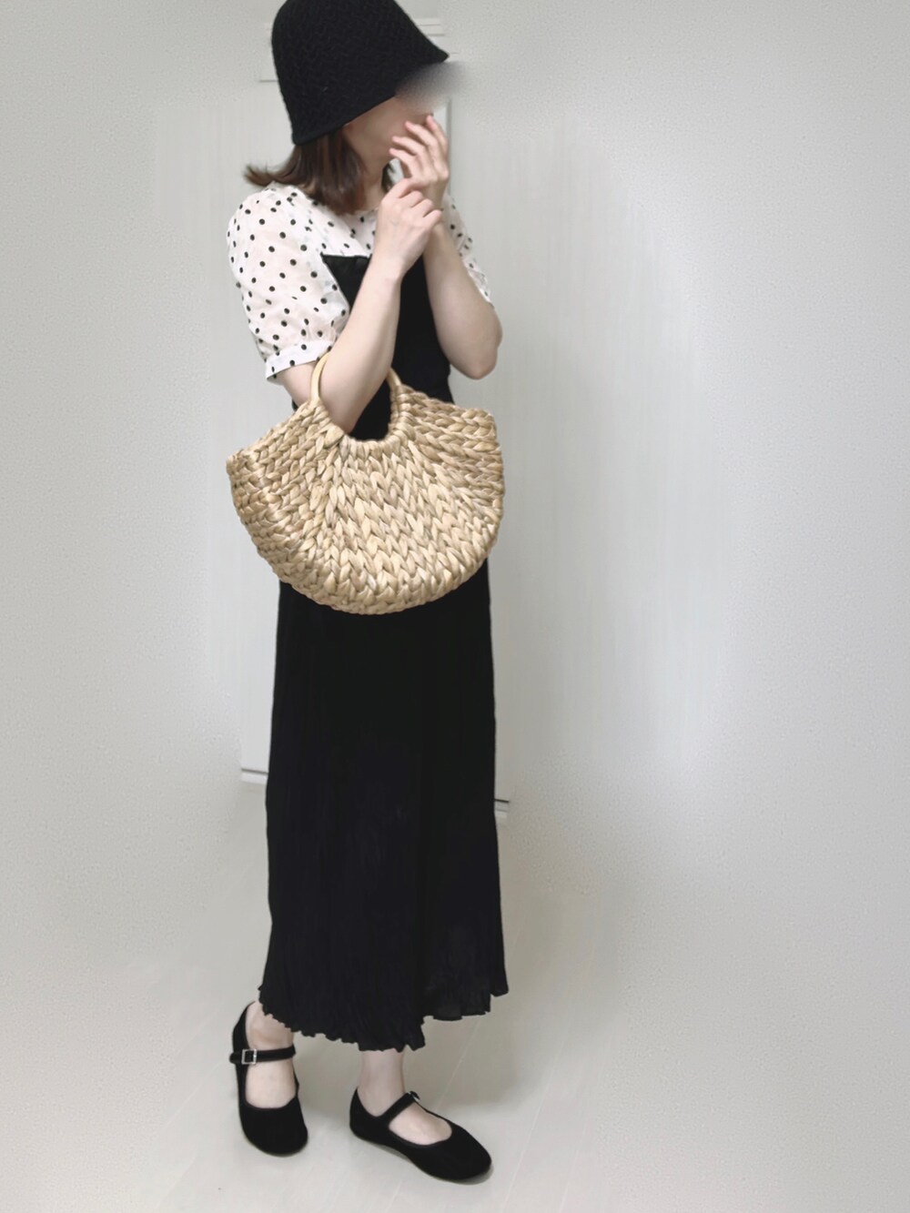 ベージュ系のかごバッグ、ブラック系のワンピース、ブラック系のパンプスを着用したレディースの夏コーディネートの3枚目の写真