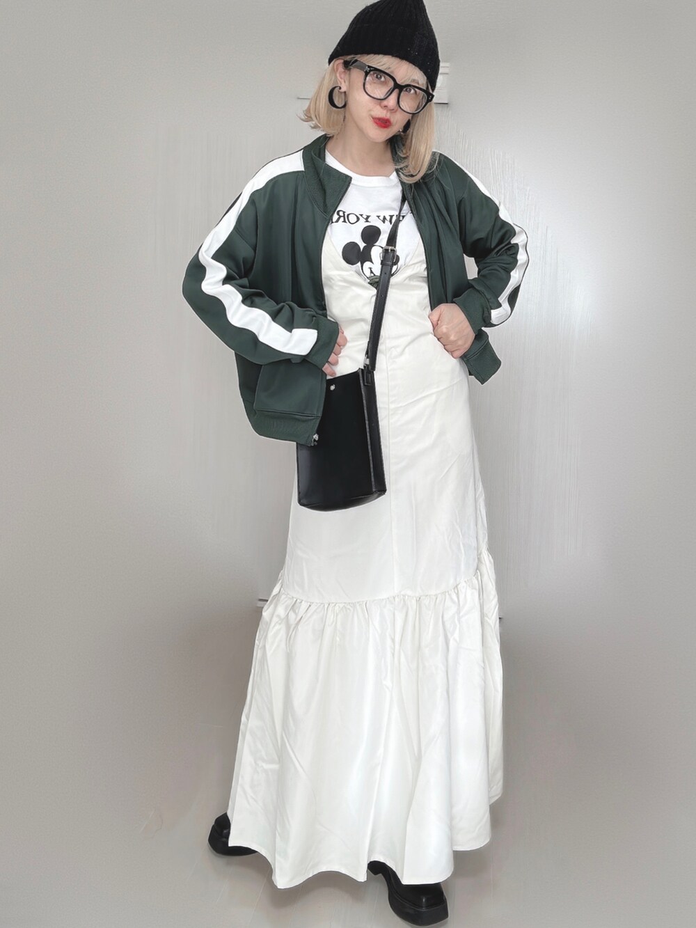 ホワイト系のジャンパースカート、グリーン系のその他アウター、ホワイト系のTシャツ/カットソーを着用したレディースの秋コーディネートの2枚目の写真